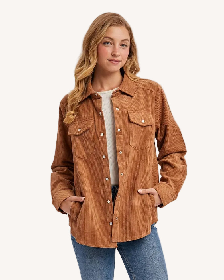 Woman wearing a brown jacket, white shirt, blue jeans, and white sneakers on a light gray background